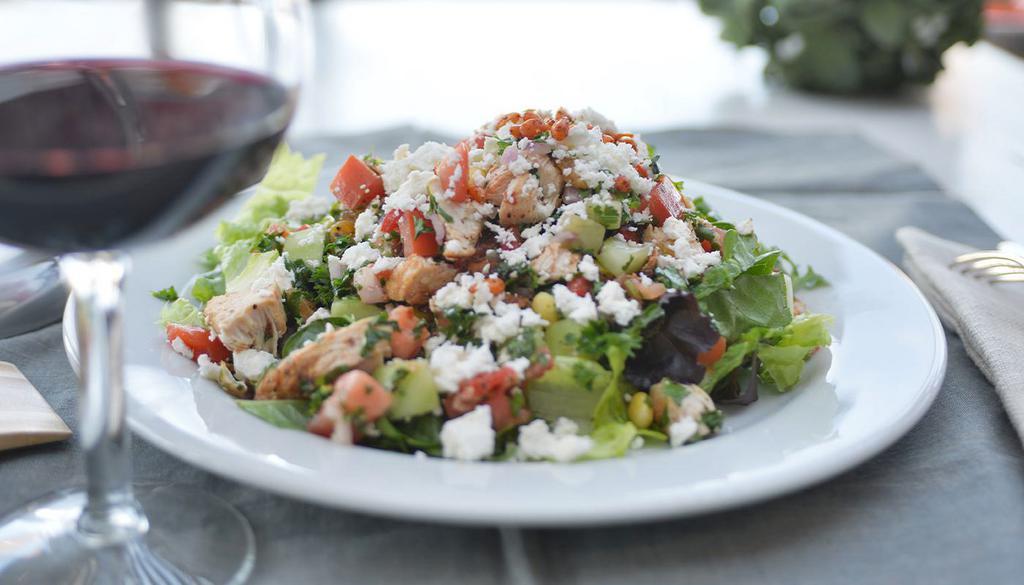 Mediterranean Chicken Salad · grilled chopped all-natural chicken breast, roasted bell peppers, cucumbers, taboule, seasonal mixed greens, corn, diced tomatoes, red onions, feta, golden raisins, toasted pine nuts, fresh cilantro and lemon vinaigrette