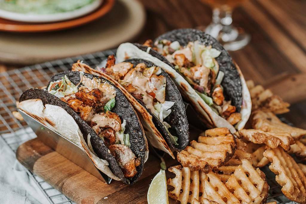 Cajun Fish Tacos · Three crispy corn tortillas wrapped in soft flour tortillas, blackened cod, pepper jack cheese, lettuce, pico de gallo, Cajun rémoulade, served with waffle fries