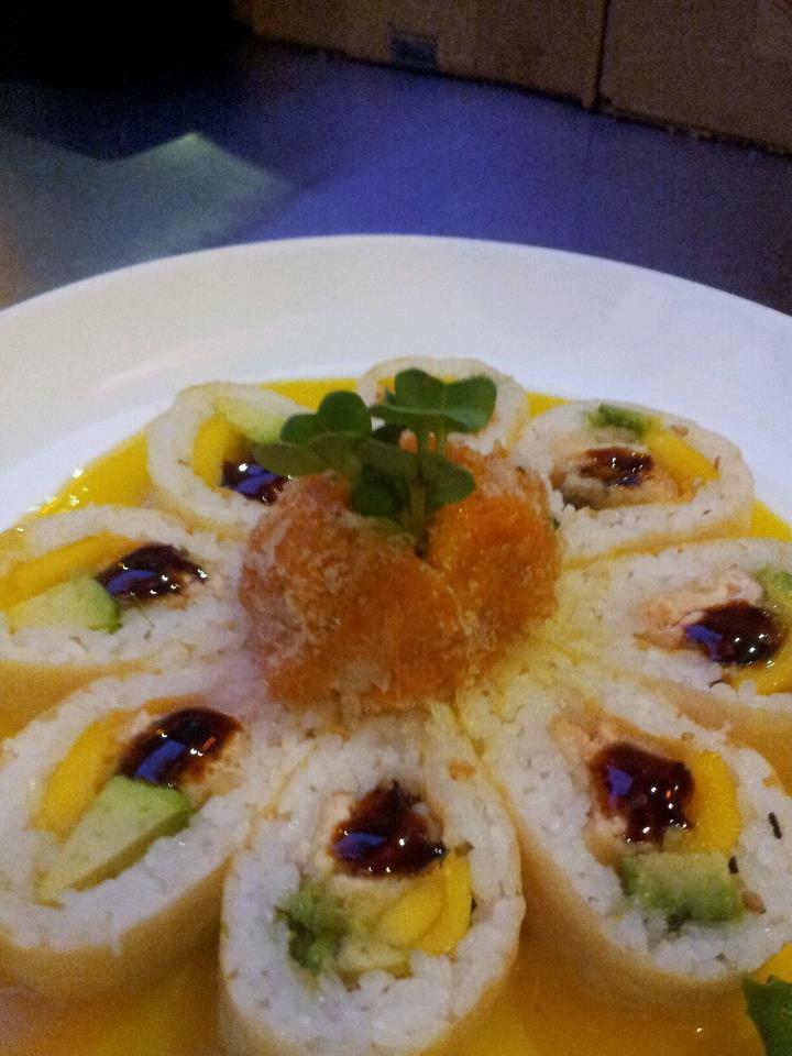 Sunflower Roll · Inside; salmon tempura, mango and avocado, wrapped by yellow soy paper and topped by spicy salmon and flower shape. 