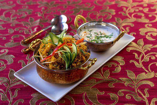 Goat Biryani · Long grain aromatic basmati rice cooked with bone-in goat meat. Flavored with Indian herbs and spices, saffron, nuts and raisins.