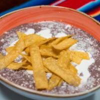 Crema de Frijol Bowl · Creamy beans soup. Classic black bean soup, tortilla strips, Cotija cheese and sour cream.