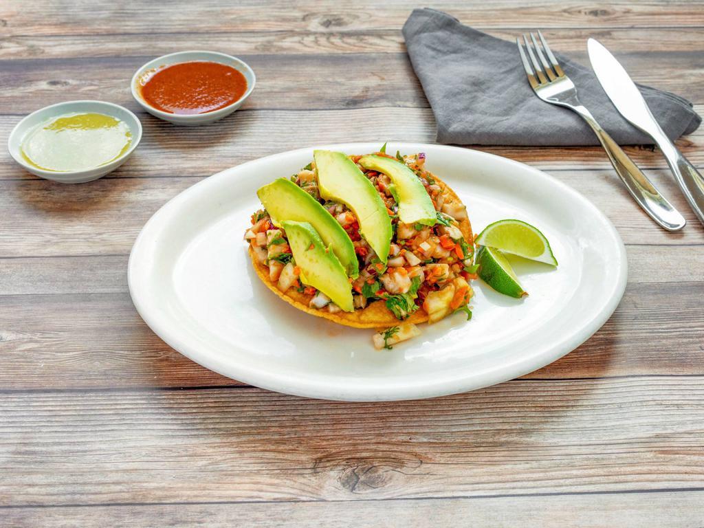 Tostada and Fish Ceviche · White fish marinated in lime juice, mixed with cilantro, chopped onions and diced carrots. Topped with avocado slices.