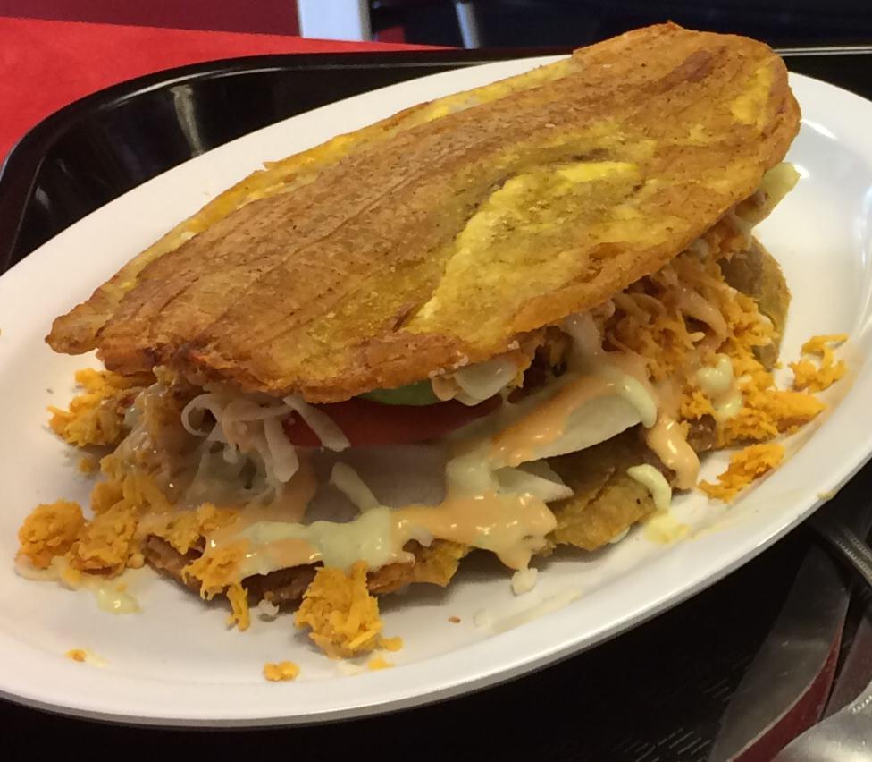 Patacon (toston) Sandwich · Sandwich of green fried plantains (Toston) filled with grilled beef or chicken or with shredded beef or chicken, mozzarella cheese, avocado, lettuce, tomato, green sauce, pink sauce and pineapple sauce.