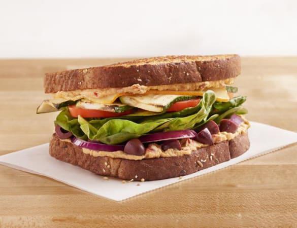 Zucchini Grillini Sandwich · Roasted zucchini, Muenster, organic spinach, red onions, Roma tomatoes, Kalamata olives, roasted red pepper hummus, toasted multigrain wheat. 