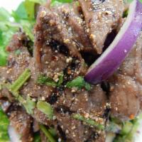 8. Beef Nahm Tok · Grilled beef seasoned with scallions, roasted rice powder, cilantro, mint, red onions, chili...