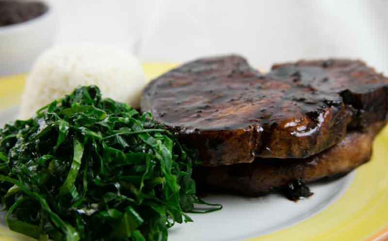 Brazilian-Style Pork Chops · Pork chops with garlic-wine sauce and sauteed collard greens. Served with Rice & Beans
