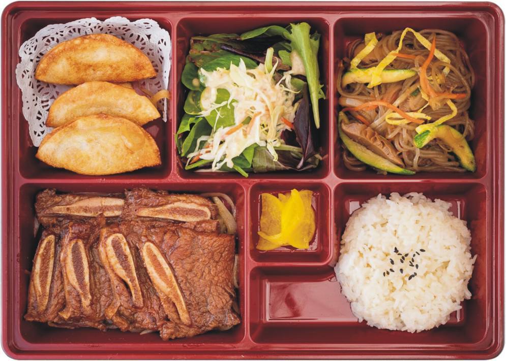 Beef Short Ribs Bento Box · Grilled and marinated beef short ribs. Served with rice, fresh seasonal salad, and stir-fried noodles with vegetables and fried dumpling. 