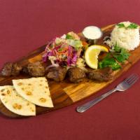 Lamb Skewered Kebab · Grilled skewer of marinated lamb. Served with the rice, salad, pita and sauce.