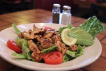 Grilled Chicken Salad  · A bowl of romaine lettuce with marinated grilled chicken and garnished with avocado fan, sli...