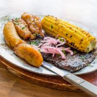 Marinated Skirt Steak · Served with roasted corn and sweet plantains on a sizzle plate.