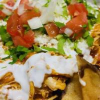 NACHOS DE TINGA · Crispy corn tortillas topped with refried beans, mozzarella, onions, tomatoes, cilantro and ...