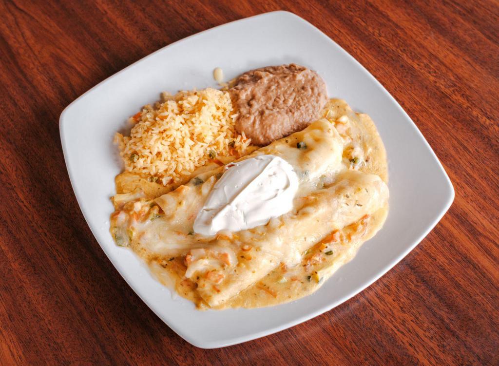 Enchiladas De Camaron · Two flour tortillas filled with spicy shrimp, poblano peppers, scallions, and tomatoes sauteed in a light ranchero cream sauce and served with sour cream.  Served with Mexican rice and refried beans.