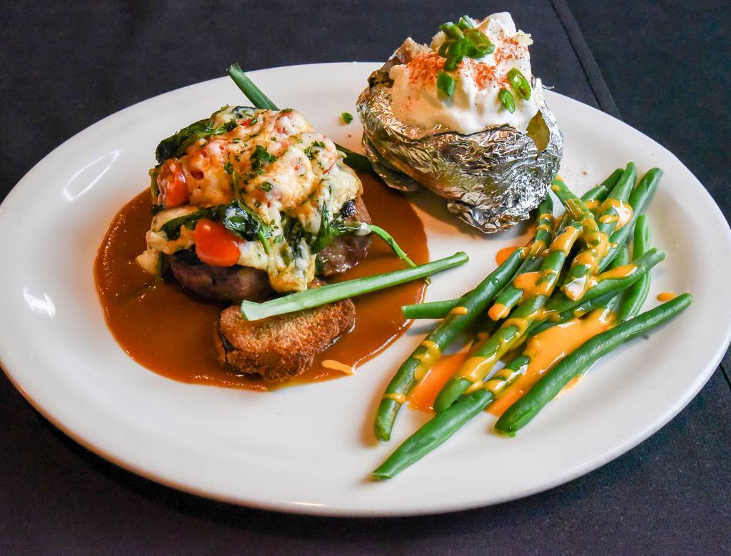 Tenderloin Asiago · Seasoned filet mignon served on grilled eggplant with spinach and diced tomatoes topped with Asiago cheese, accompanied by a Marsala wine sauce.