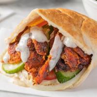 The Chicken Shawarma  · (One of our customers favorites)A hand made pita lined with hummus, stuffed with ,fire spit-...