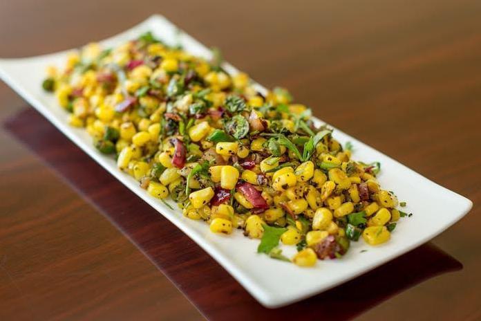 Spicy Corn · Sauteed corn with fresh tomatoes, onion and peanut spicy dressing.