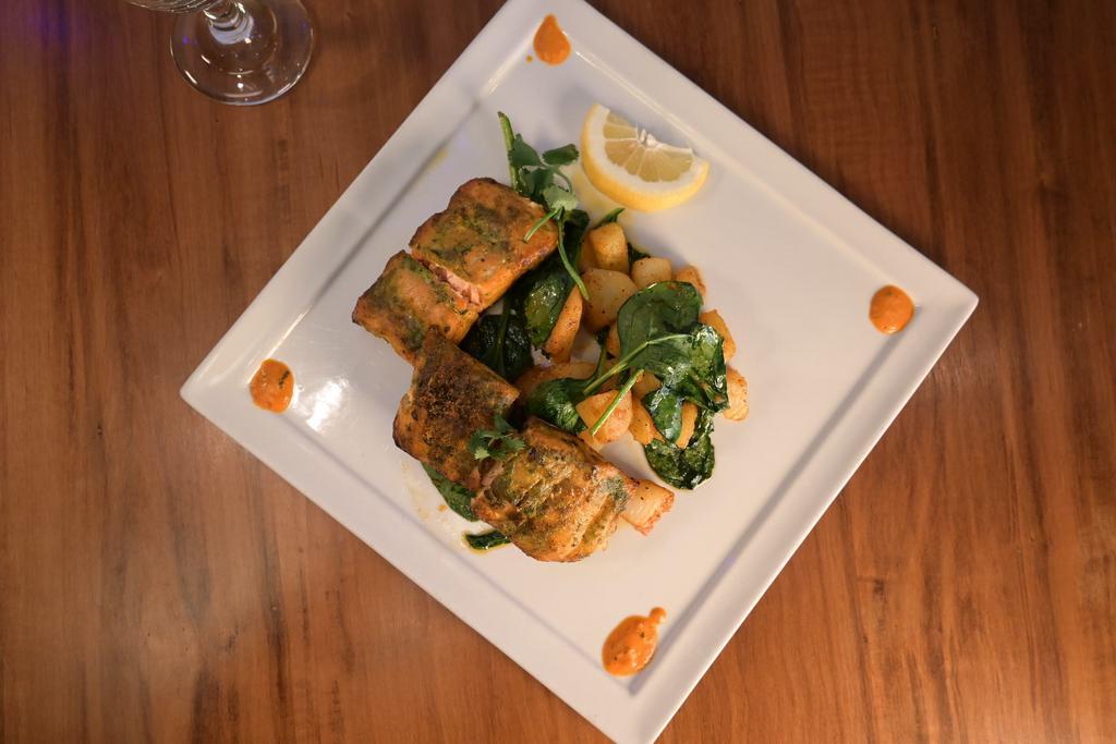 Tulsi Machhi-D · Salmon fillets marinated in a basil-based marinade, cooked in cylindrical clay oven. Served with vegan basmati rice and choice of seasonal vegetables or fresh spinach and potatoes. Gluten free.