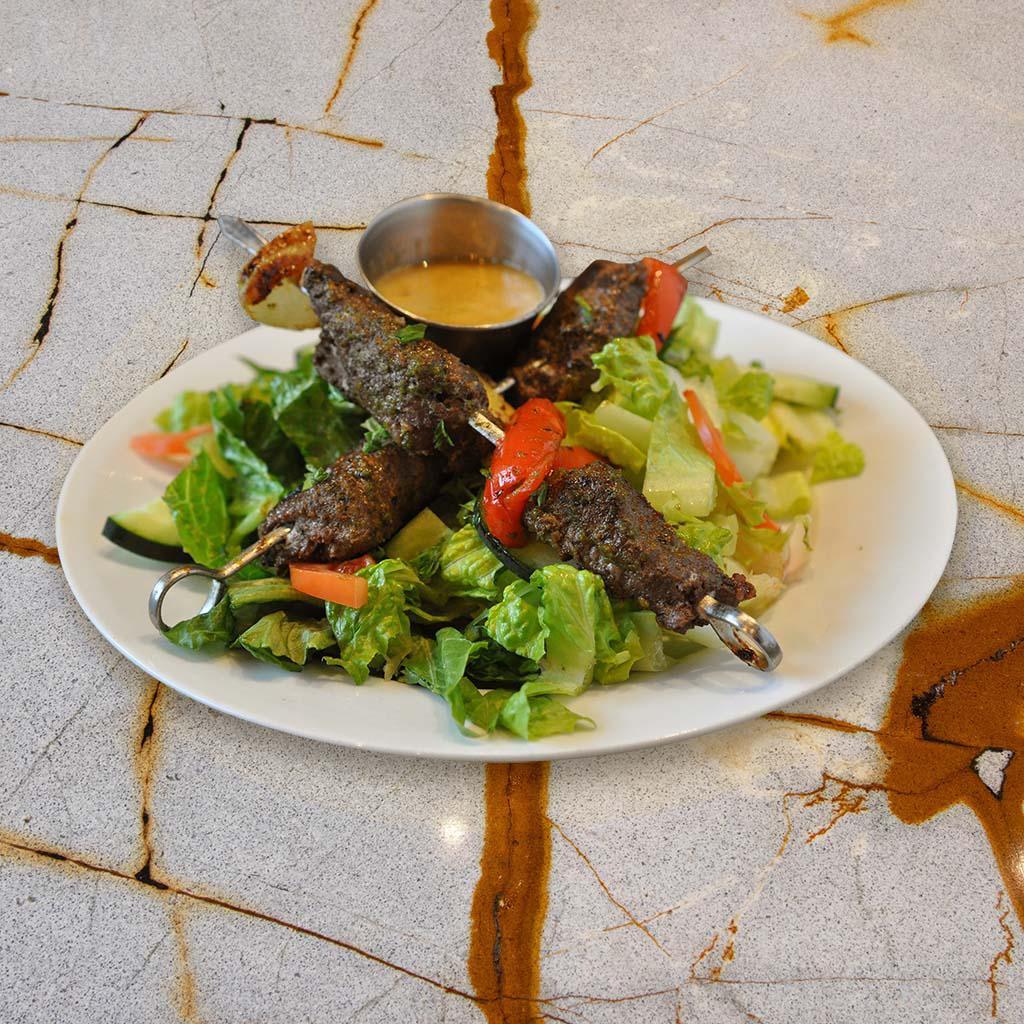 Lamb Kabob Salad (GF) · Grilled marinated lamb pieces over crispy romaine lettuce, tomatoes, cucumbers, and parsley, with our tangy lemon garlic dressing. 