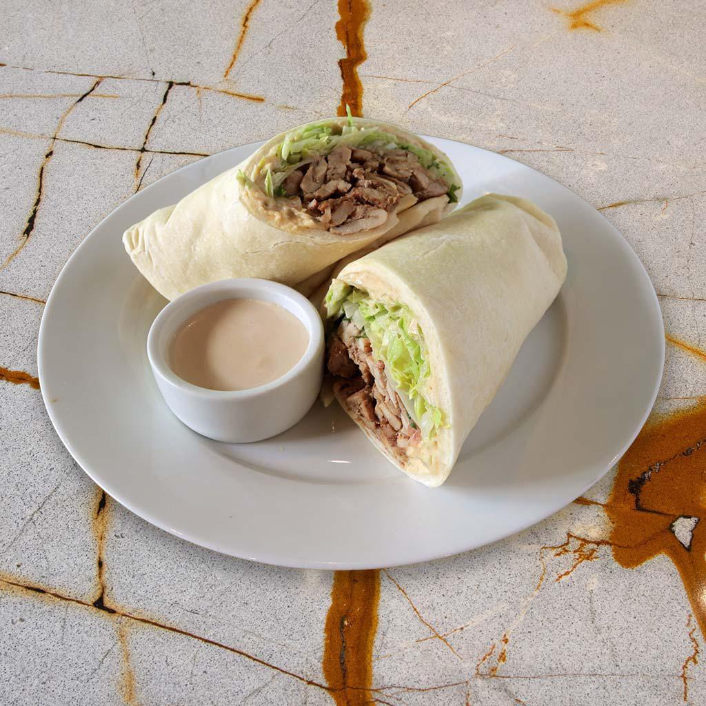 Chicken Shawarma Sandwich · Original hummus, grilled chicken marinated with garlic, lemon and spices served on our house pita bread with lettuce, tomato, onion and our garlic tahini sauce.