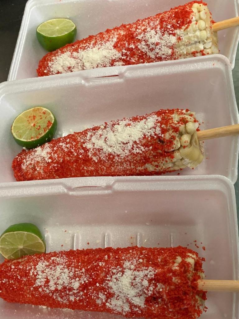Elote Entero con Hot Chetos · Corn on the cob with a mayo base and covered in hot cheetos! with cotija cheese on top and a fresh lime on the side. Elote entero con base de mayonesa y hot cheetos alrededor del elote con queso cotija y un limon fresco al lado.