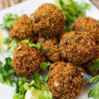 Falafel Entree · Chunks of falafel balls served over a bed of hummus with rice and vegetables on the side.