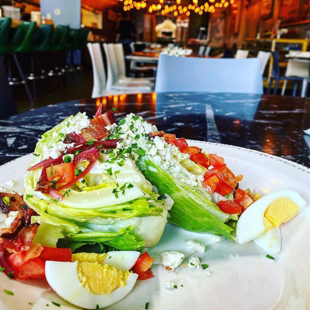Wedge Salad · Iceberg lettuce wedge topped with hard boiled egg, tomato, pickled red onion, cherry smoked bacon and creamy bleu cheese dressing