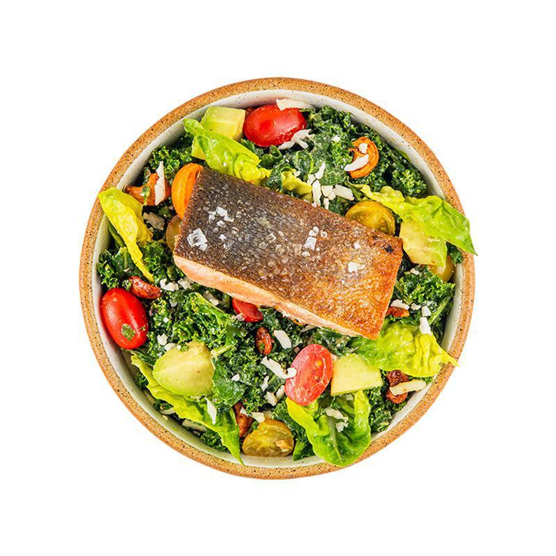 Alaskan Salmon Kale Caesar Salad · Cashew Kale Caesar, farm greens with mint, wild Alaskan salmon, avocado, shaved cauliflower, cherry tomatoes, spicy cashews, toasted breadcrumbs, and more cashew Caesar dressing on the side.  Contains wheat/gluten, tree nuts (cashew), fish.