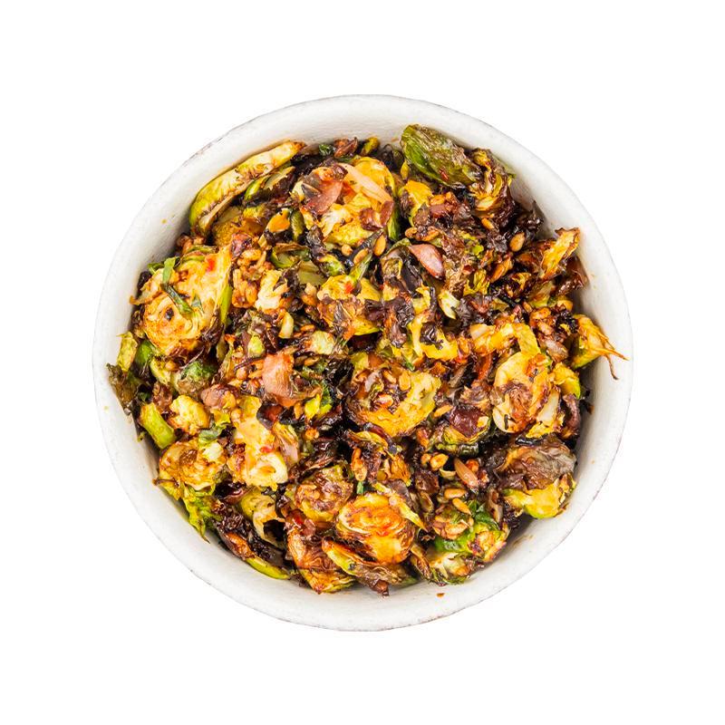 Roasted Brussels Sprouts - Side · Shaved brussels sprouts, roasted with grilled onion, dressed in a maple sriracha sauce with candied sunflower seeds. Vegan.