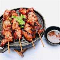 GARLIC PORK STICKS · 4 pieces. Moo pieng. Grilled pork skewers marinated in garlic and Thai spices. Served with s...