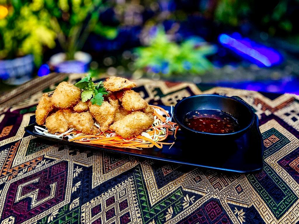 CRISPY FRIED CALAMARI · Tod pla muk. Calamari strips marinated and breaded in Thai spices, deep-fried golden. Served with sweet chili sauce.