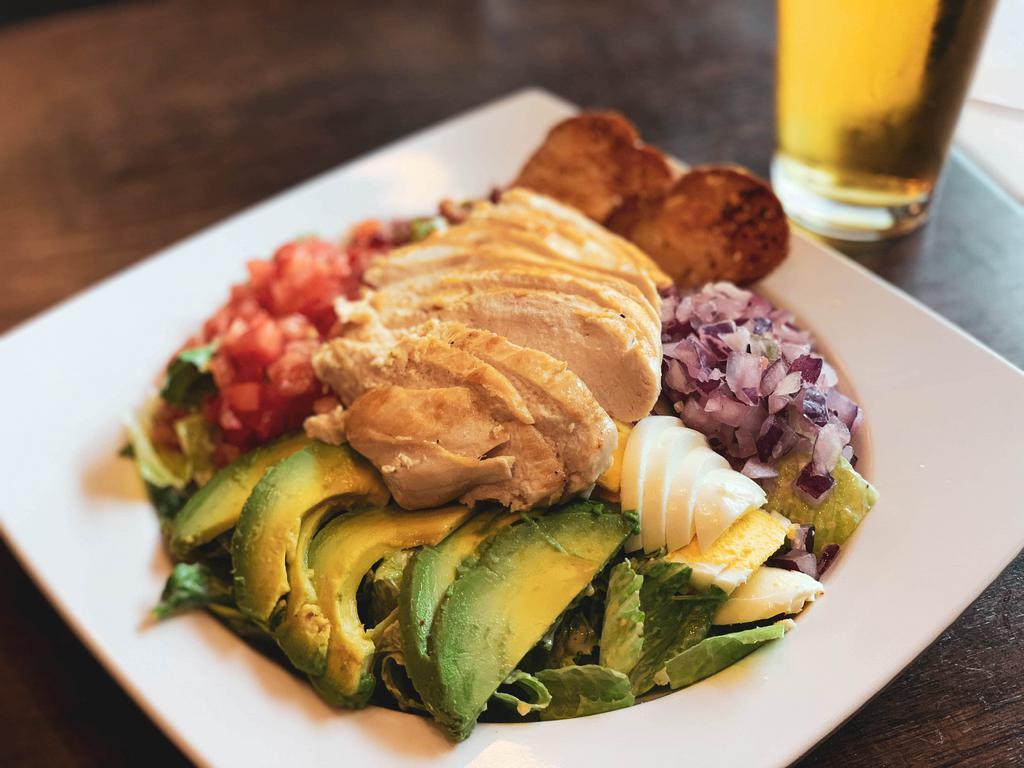 Cobb Salad · Grilled chicken, boiled egg, avocado, bacon bits, tomato, red onion, romaine, blue cheese dressing and garlic Parmesan crostini.