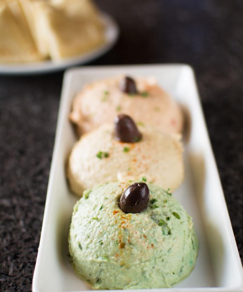 Hummus Trio · Choice of three from traditional, roasted red pepper, roasted garlic, jalapeño cilantro, smoked chipotle, sun-dried tomato. Served with pita.