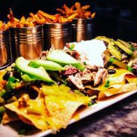 Pulled Pork Nachos · Covered in cheese sauce, black beans, green onion, green chiles, avocado, sour cream, and ci...