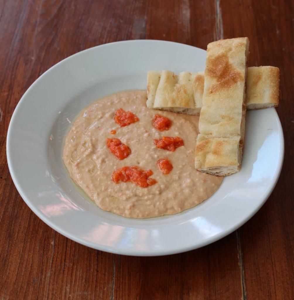 Sicilian White Bean Hummus · Italian hummus made with white bean instead of chickpeas garnished with a dollop of roasted red pepper/garlic puree and finished with a drizzle of olive oil. Vegan. Select the Gluten Free option for a side of celery instead of focaccia.