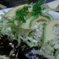 Enchiladas de Mole Negro · Enchiladas topped with lettuce, onions, queso fresco, and avocado. 