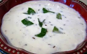 Raita · Yogurt with bits of cucumber, tomatoes, garnished with cilantro and mint.