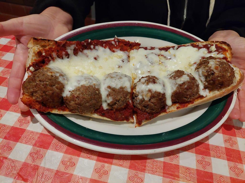 Pasquale's Italian Meatball Sandwich · Our sub roll lightly covered with butter, garlic and our special meat sauce. Then we top with 6 large meatball halves smothered in mozzarella and Parmesan cheese and lightly baked to perfection. Garnished with wax peppers.