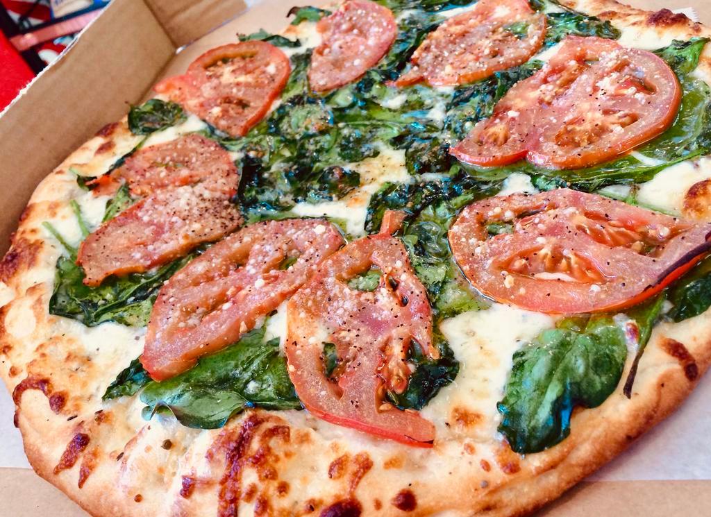 Tomato N' Spinach White Pizza · Our Thin Crust White Pizza made with Fresh Garlic, Corto® Olive Oil & Spices, Freshly Shredded Mozzarella, Fresh Baby Spinach, Sliced Tomatoes, seasonings and a little extra Mozzarella & Romano Cheese over the top.