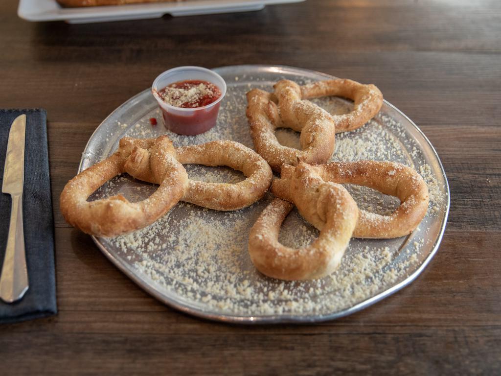 Parmesan Pretzels · Made with our classic dough, served coated in garlic butter, Parmesan, and a side of mellow red sauce or coated with garlic butter, kosher salt, and served with traditional yellow mustard.