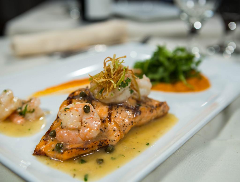 Mancora Salmon · Grilled fresh salmon fillet with capers sauce, lime juice, topped with shrimp,  on a bed of sweet potato and veggies. 