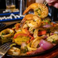 Grilled Seafood · Grilled seafood octopus, squid tubes, and shrimp topped with a yellow pepper chimichurri sau...