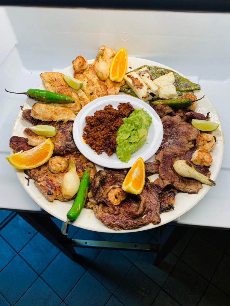 Fiesta Molcajete · Choice of guacamole or cheese dip, served with chorizo, pork chops, steak, chicken, shrimp, black beans, rice, retired beans, green or red salsa garnished with oranges, limes, pencil onions, jalapenos and nopales. 
(Serves 2-4 people) 