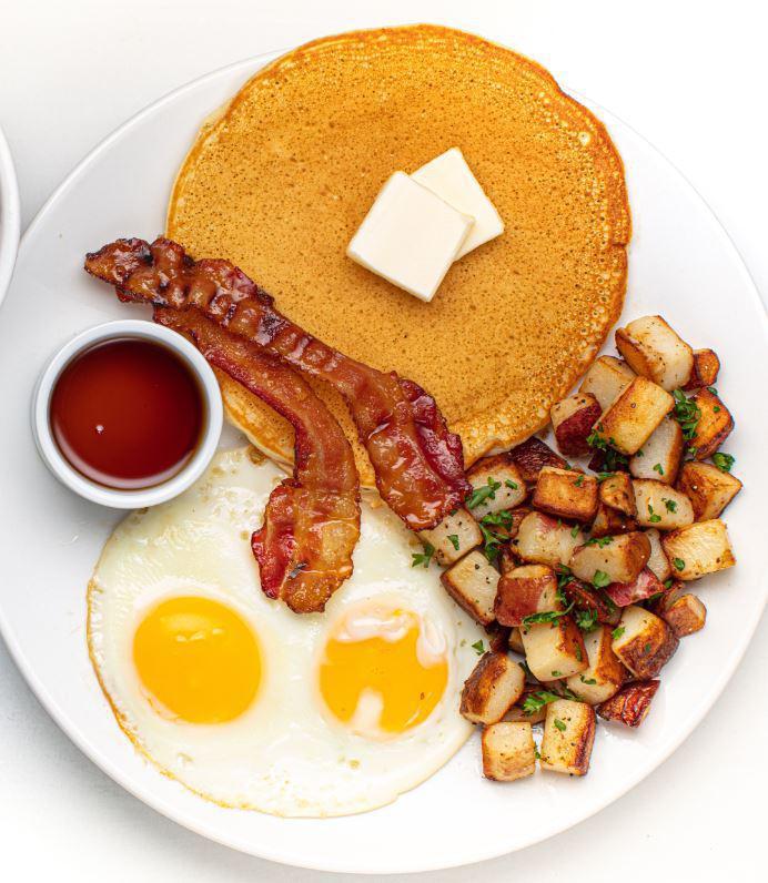Traditional Buttermilk Pancakes · Two Buttermilk Pancake, Two Eggs Any Style, Grilled Homestyle Potato, Double Smoked Applewood Caramelized Bacon, Served with a Side of Maple Syrup