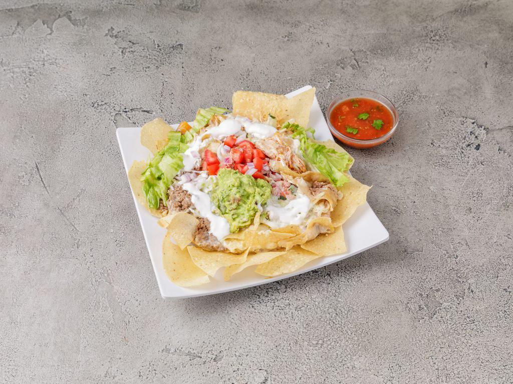 Nachos Supreme · creamy cheese sauce, ground beef, shredded chicken and refried beans. Topped with shredded lettuce, guacamole, pico de gallo and sour cream.