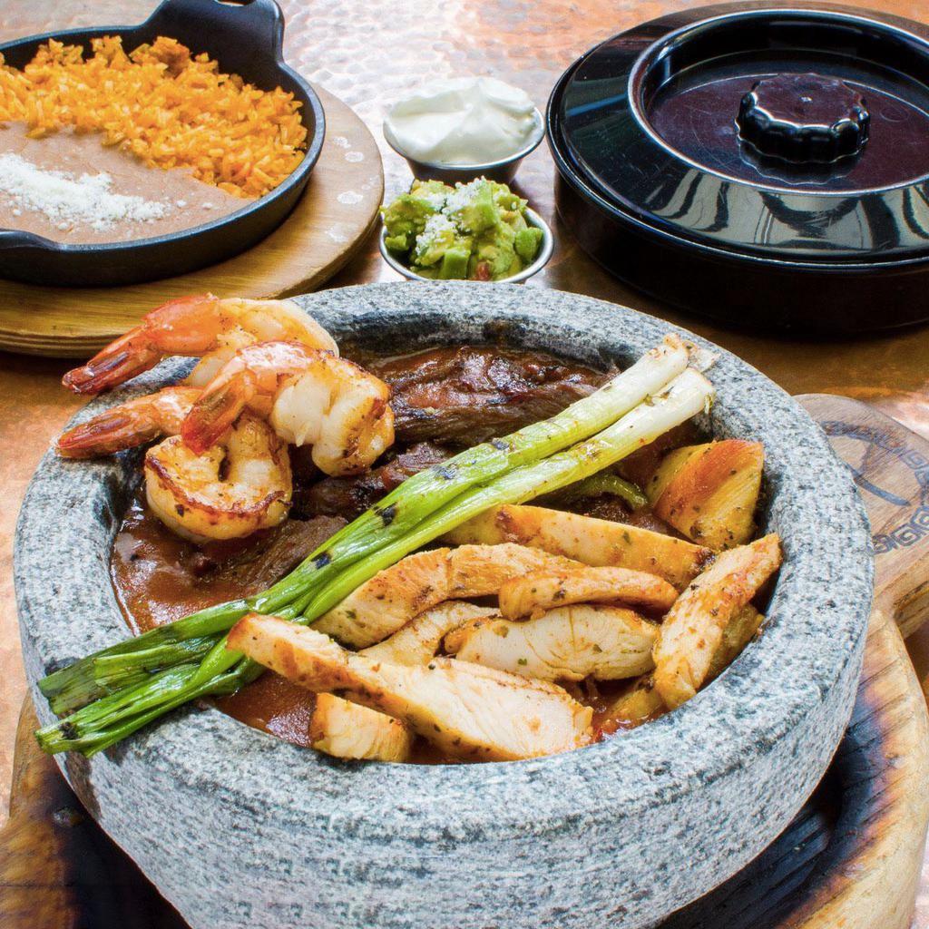 Molcajetes · Authentic mexican spicy stew made with your choice of meat combined with poblano peppers, onions, chorizo, green onions and cheese served with tortillas, pico de gallo, sour cream, and rice and beans.