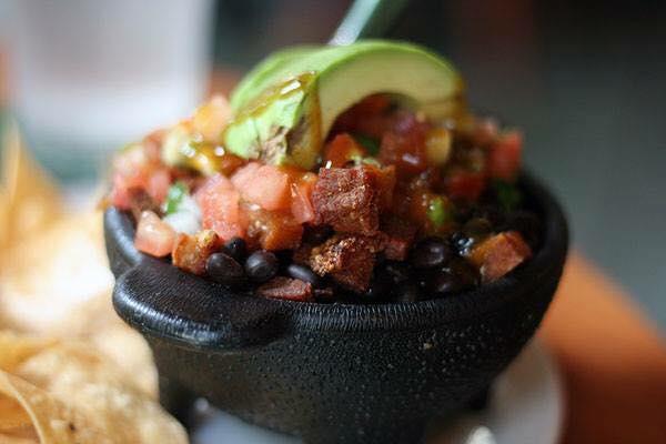 Chifrijo Fiesta Tray · An authentic starter to your meal. Fried pork is layered with whole black beans, white rice, pico de gallo, and topped with avocado and Salsa Lizano. Served with chips. Highlighted on the Food Network's 