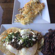 Huevos Rancheros · Crisp corn tortillas, pulled pork, aged cheddar and 2 eggs any style, topped with salsa, feta and cilantro. Served with black beans and hash browns.