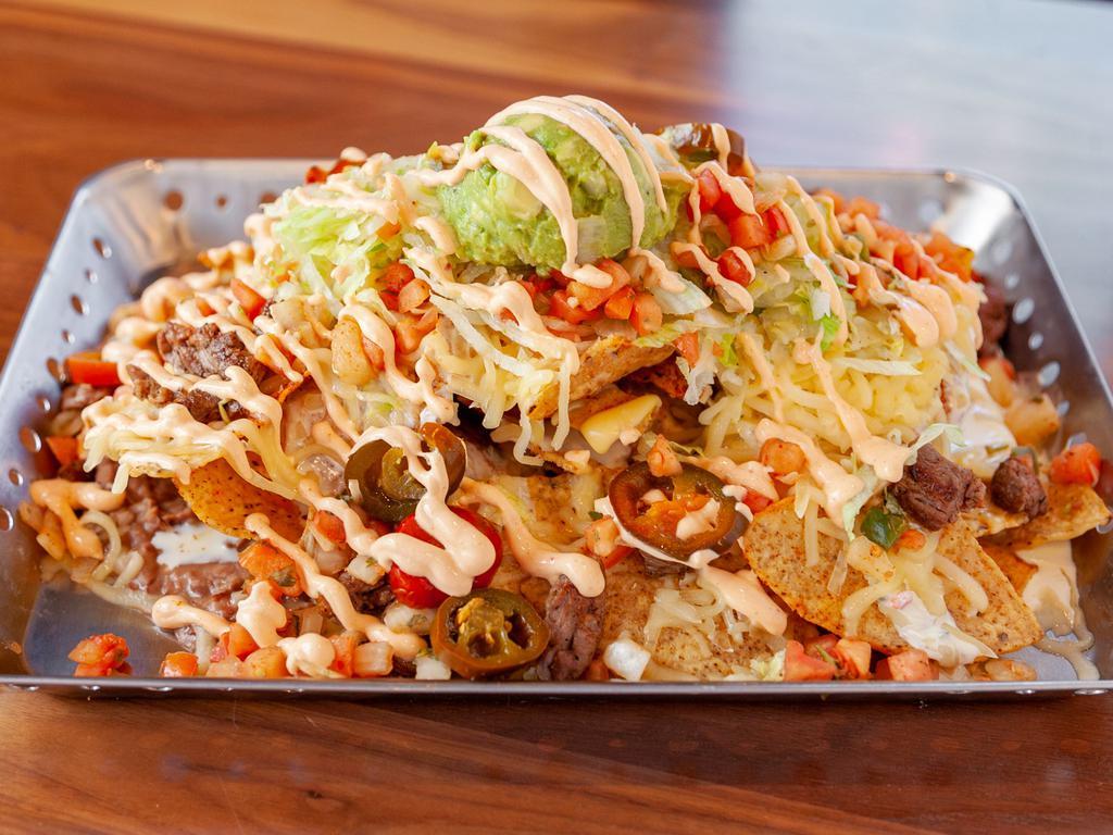 Macho Nachos · Crisp corn tortilla chips topped with white queso, cheddar and Chihuahua cheeses, olives, salsa, refried beans, pico de gallo and jalapenos, topped with shredded lettuce, Cholula sour cream and guacamole. Add-ons for an additional charge.