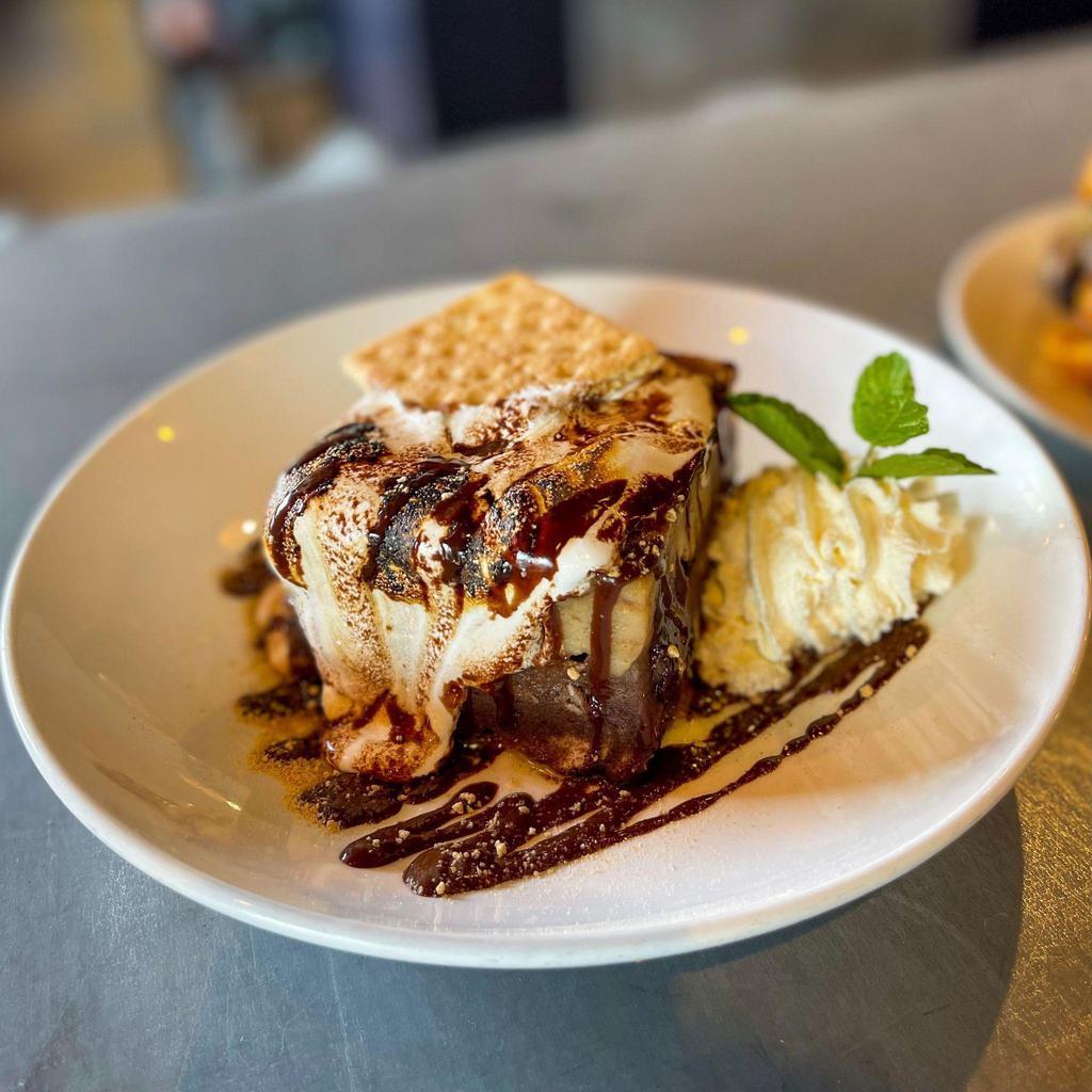 Bread Pudding · Chocolate & marshmallow layered bread pudding, graham cracker cookie butter, toasted flu, & finished with chocolate
porter ganache & a graham cracker. Shareable.