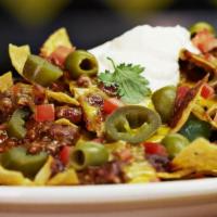 Nachos · Warm corn tortilla chips topped with melted cheddar and pepper jack cheeses, chili, olives, ...