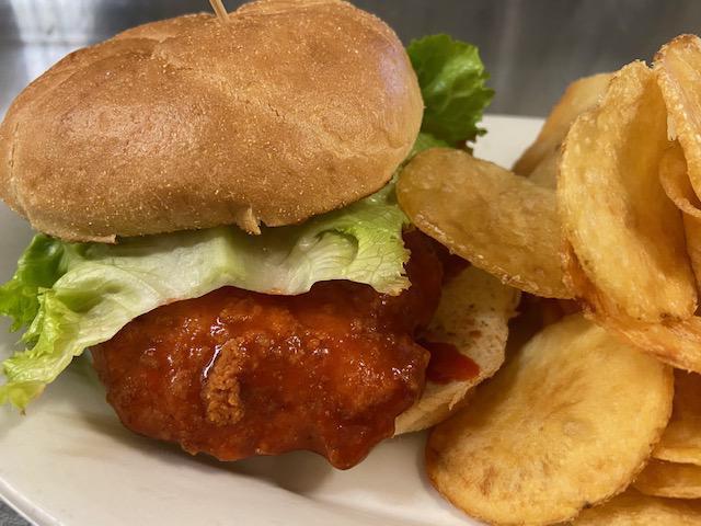 Buffalo Chicken Sandwich · Boneless chicken fried to perfection, tossed in a zesty hot sauce and topped with lettuce and tomato, served on a grilled kaiser roll. Served with your choice of a side. Premium sides available.